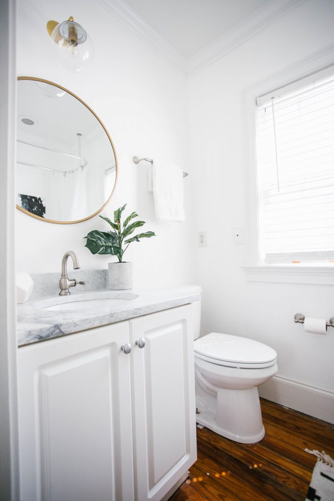 Guest Bathroom Reveal Modern Historic Downtown Charleston Home Renovation   // Charleston Fashion Blogger Dannon Almost Happening    Urban Outfitters black hexagon hand towel ring DIY cedar and moss brass sconce white clawfoot tub shower round brass vanity mirror target cement planter hex white vase white walls marble cararra countertops black and white geometric kilum rug nate burkus