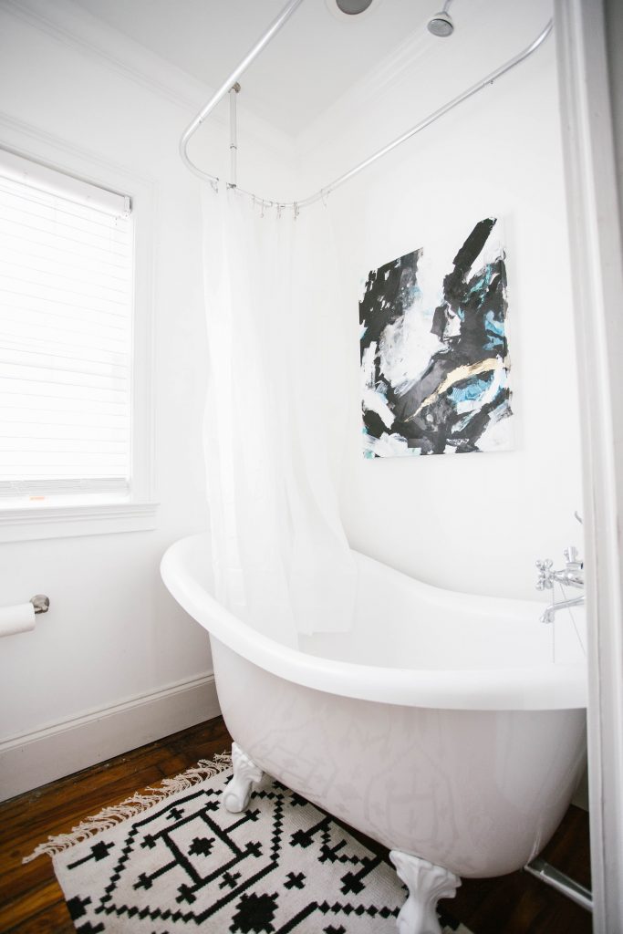 Guest Bathroom Reveal Modern Historic Downtown Charleston Home Renovation   // Charleston Fashion Blogger Dannon Almost Happening    Urban Outfitters black hexagon hand towel ring DIY cedar and moss brass sconce white clawfoot tub shower round brass vanity mirror target cement planter hex white vase white walls marble cararra countertops black and white geometric kilum rug nate burkus